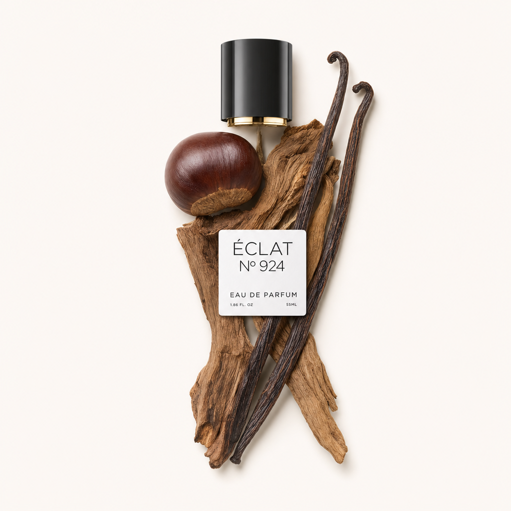 Una composizione artistica di ÉCLAT Smoky Chestnut include un tappo nero lucido con accento dorato, una castagna intera, baccelli di vaniglia profumati ed elementi di legno strutturato.