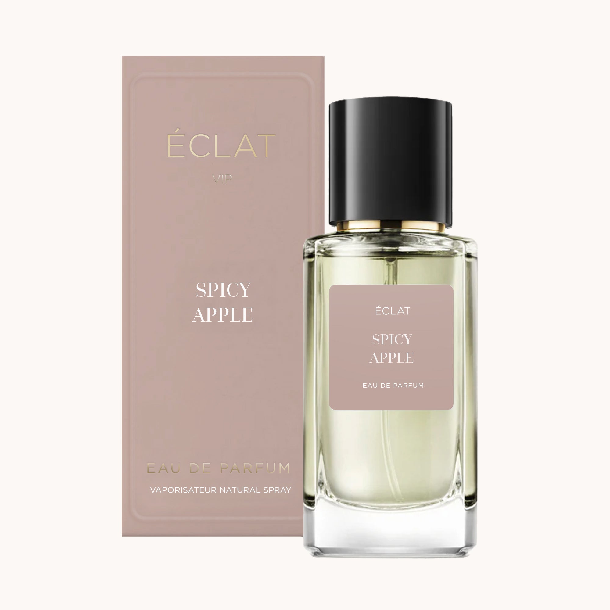 Un flacone di vetro sfaccettato di ÉCLAT Spicy Apple con tappo nero si trova accanto a una scatola opaca in rosa tenue.