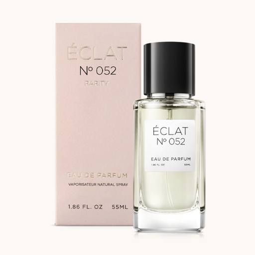 Un flacone di vetro sfaccettato di ÉCLAT Spicy Milk con tappo nero, accompagnato da una scatola rosa tenue.