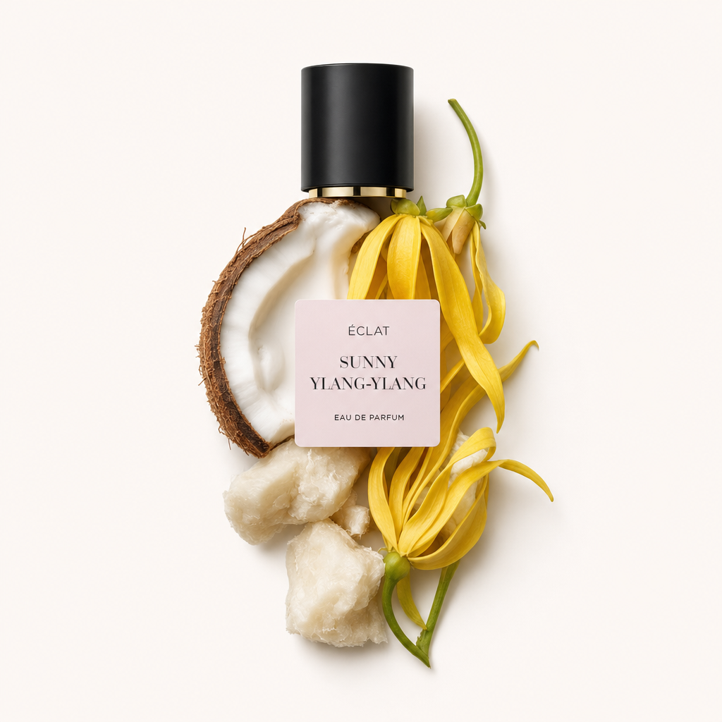 Una composizione di fiori freschi di ylang-ylang, mezza noce di cocco e pezzi di burro di karité, con un tappo nero etichettato ÉCLAT Sunny Ylang-Ylang.