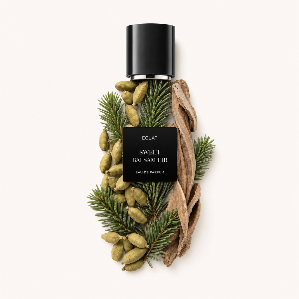 Un arrangiamento di ramoscelli di abete balsamico, baccelli di cardamomo e trucioli di legno circonda un cappuccio nero con etichetta ÉCLAT Sweet Balsam Fir.