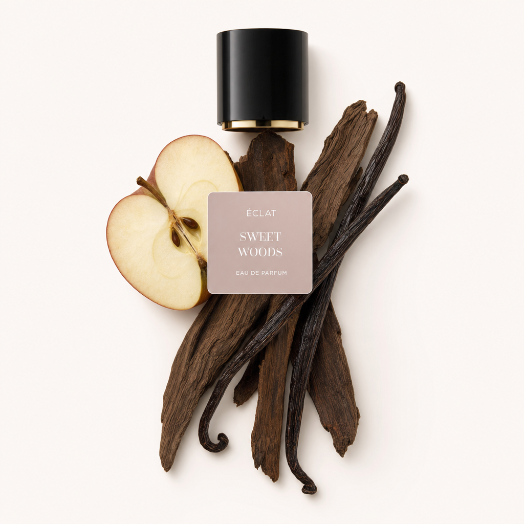 Un arrangiamento di fettine di mela, baccelli di vaniglia e bastoncini di legno crea una composizione naturale sotto l'etichetta ÉCLAT Sweet Woods e il tappo nero originale.