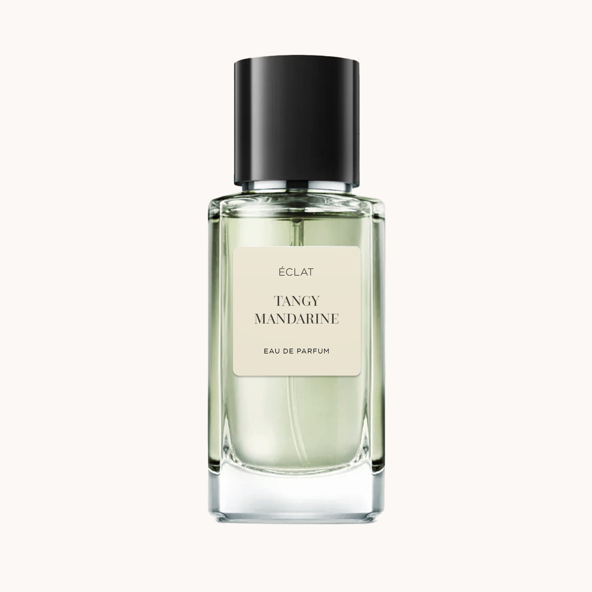 Un flacone trasparente di profumo ÉCLAT Tangy Mandarine con tappo nero ed etichetta crema.