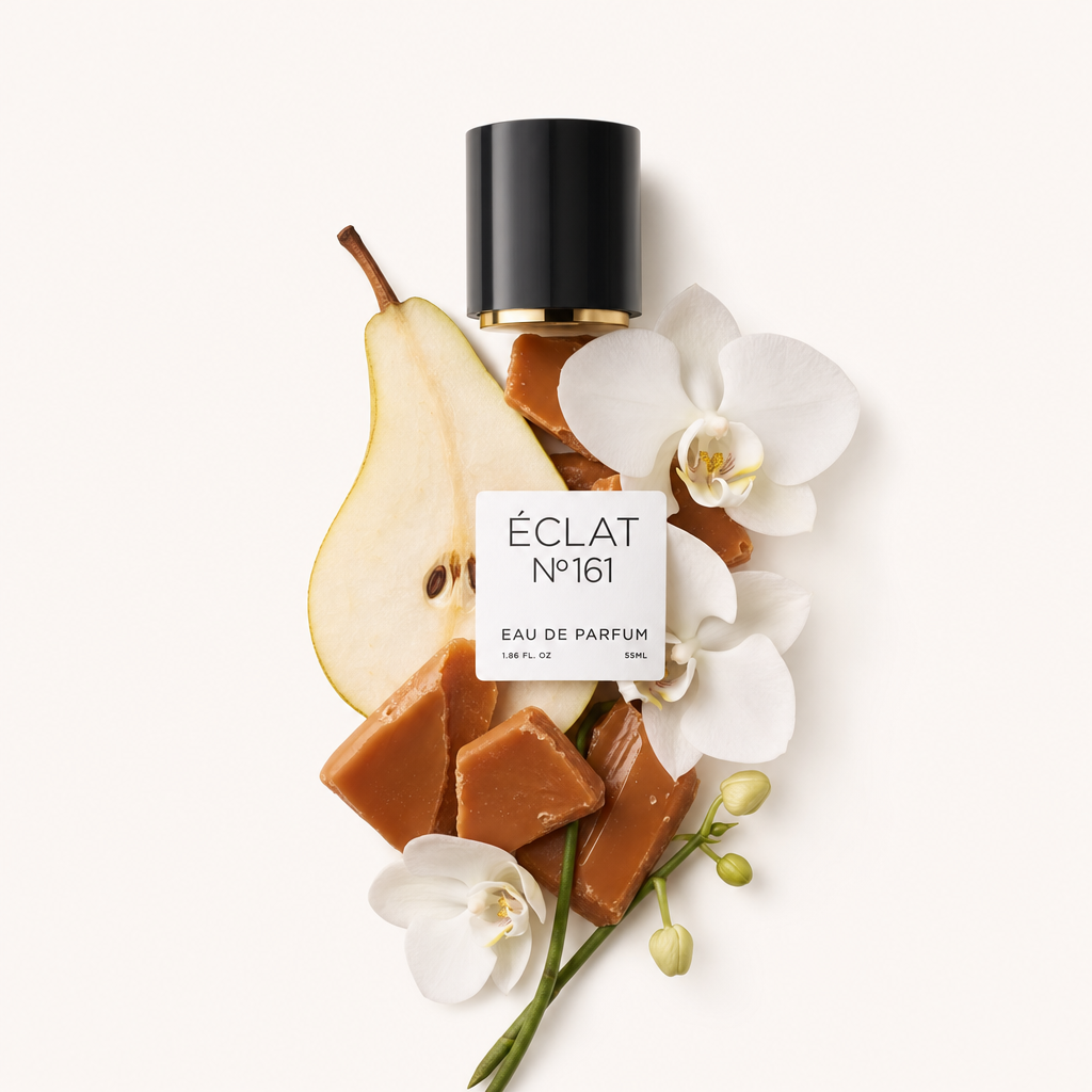 Una composizione di pezzi di toffee, una fetta di pera e fiori di orchidea bianca è elegantemente disposta accanto a un tappo nero con un'etichetta riportante il testo ÉCLAT Toffee & Patchouli.