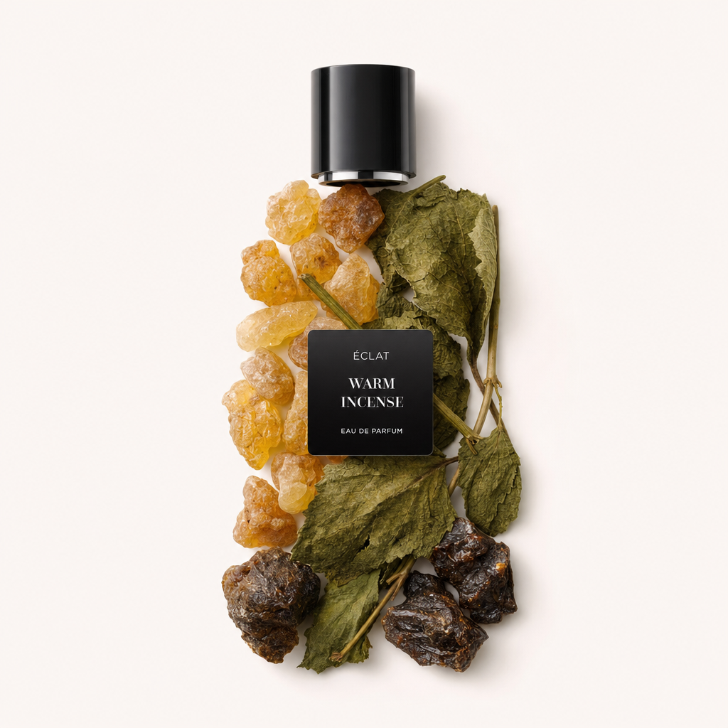 Un arrangiamento di resina d'ambra, foglie secche e componenti scuri d'incenso, sormontato da un tappo nero etichettato ÉCLAT Warm Incense.