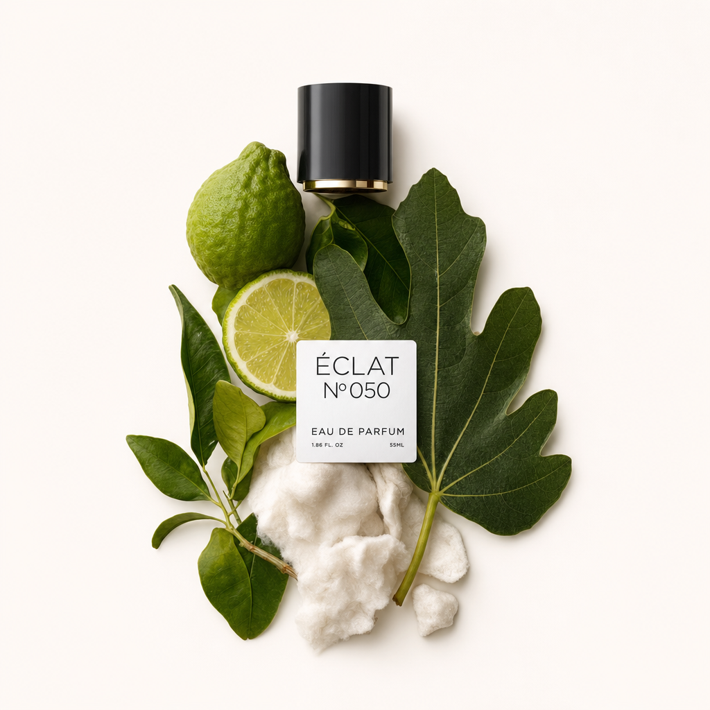 Una composizione di agrumi, foglie verdi e morbide fibre bianche, con un tappo nero con etichetta ÉCLAT White Musk & Citrus Fruits.