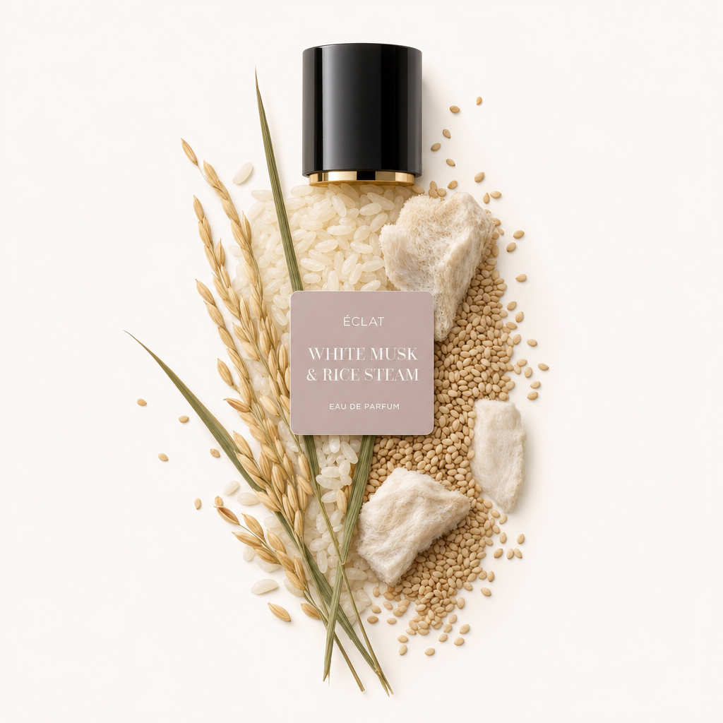 Una disposizione artistica di chicchi di riso, pezzi di muschio soffice e cereali circonda un tappo nero con un'etichetta ÉCLAT White Musk & Rice Steam.