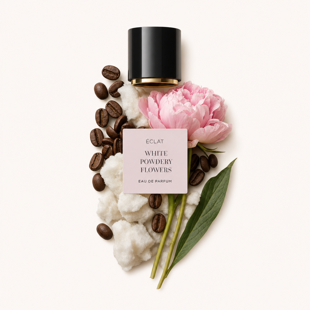 Un arrangiamento di cotone, chicchi di caffè e una peonia rosa accanto a un tappo nero con un'etichetta che riporta ÉCLAT White Powdery Flowers.