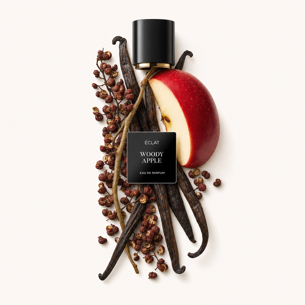 Un arrangiamento con una fetta di mela rossa, baccelli di vaniglia e bacche di spezie circonda un tappo nero con etichetta di ÉCLAT Woody Apple.