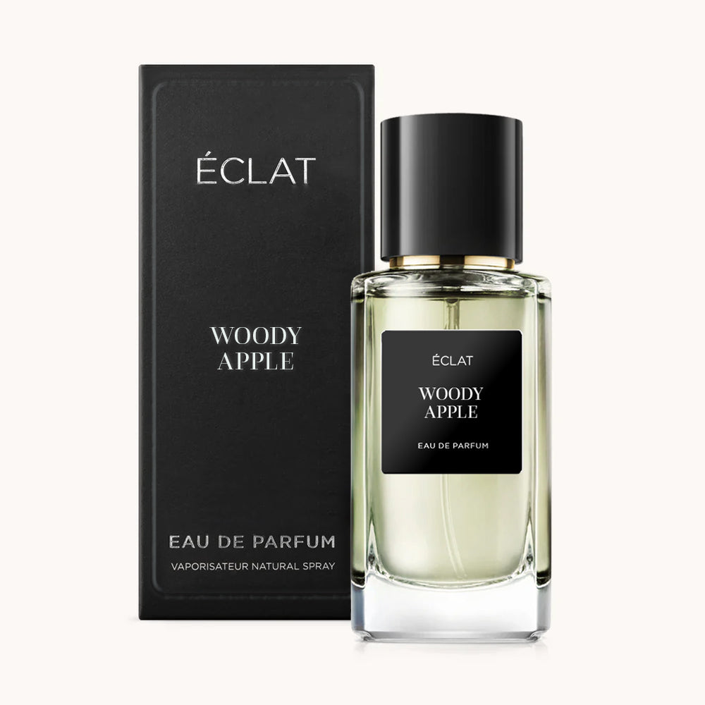 Un flacone di vetro sfaccettato di ÉCLAT Woody Apple con tappo nero, accompagnato dalla scatola nera abbinata.