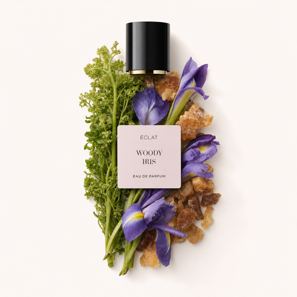 Un arrangiamento di iris viola vivaci e fogliame verde con pezzi di resina simili all'ambra circonda il tappo nero originale etichettato per ÉCLAT Woody Iris.