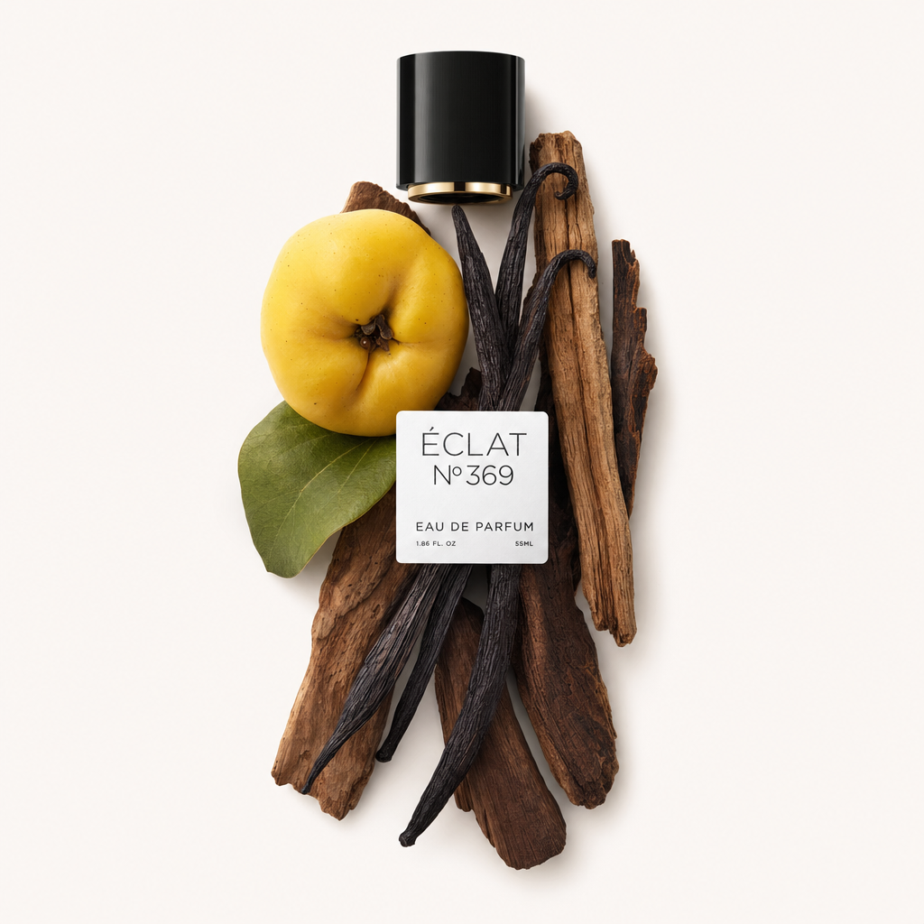 Un arrangiamento di baccelli di vaniglia, una mela cotogna gialla con foglia verde e bastoncini di legno attorno a un tappo nero con etichetta di ÉCLAT Woody Vanilla.