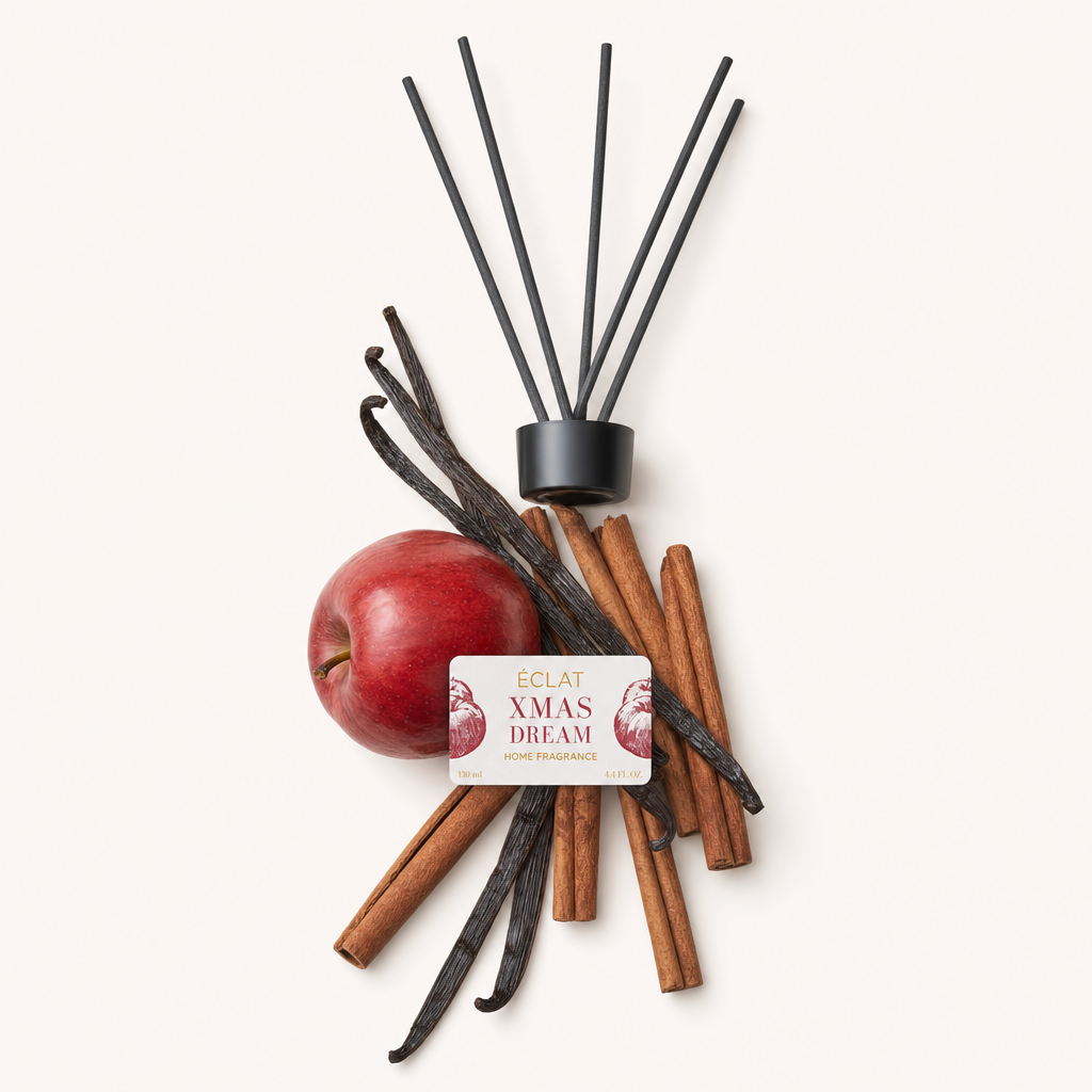 Un arrangiamento di una mela rossa, bastoncini di cannella e baccelli di vaniglia per ÉCLAT Xmas Dream Room Fragrance Sticks, accanto al tappo nero originale con etichetta.